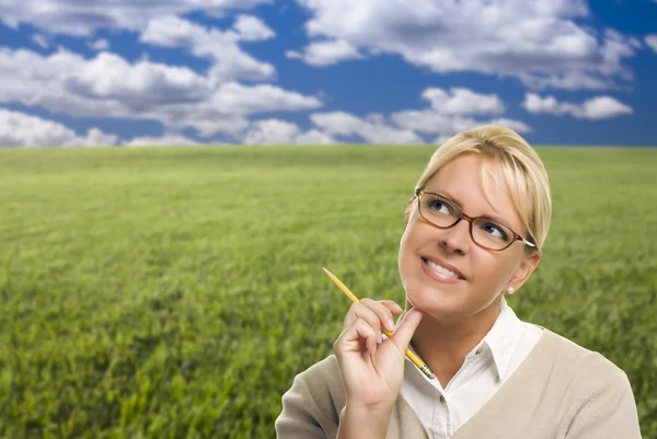 Contemplatieve vrouw in het gras veld kijken omhoog en over — Stockfoto