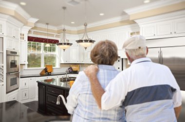 Senior Couple Looking Over Beautiful Custom Kitchen clipart