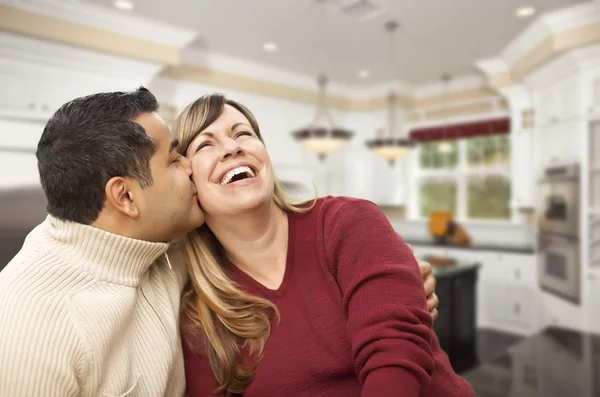 Casal de corrida mista beijando dentro da bela cozinha personalizada — Fotografia de Stock