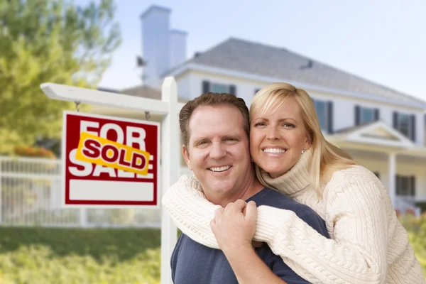 Pareja frente a nueva casa y signo vendido — Foto de Stock