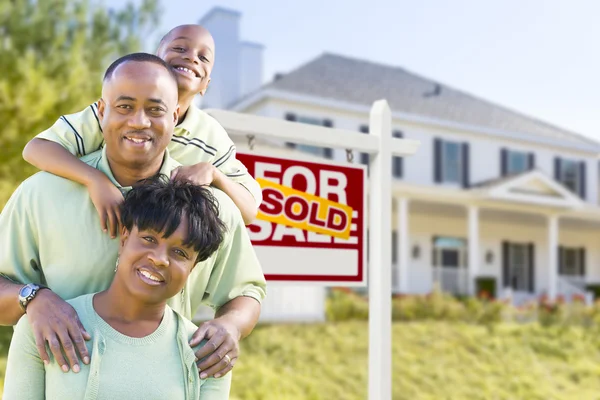 Familia afroamericana frente a letrero y casa vendidos — Foto de Stock