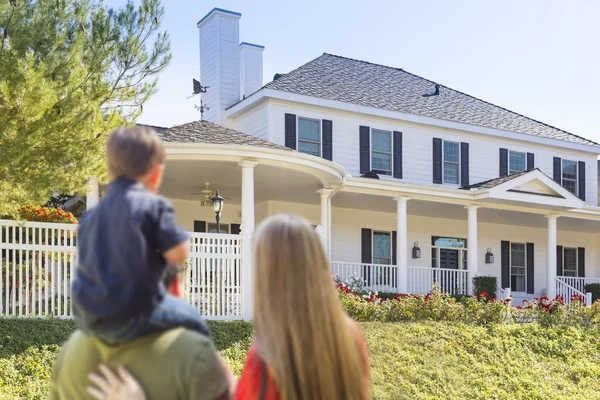 Familia joven de raza mixta mirando a una hermosa casa — Foto de Stock