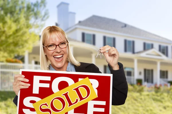 Excited Woman Holding House Keys and Sold Real Estate Sign Stock Photo