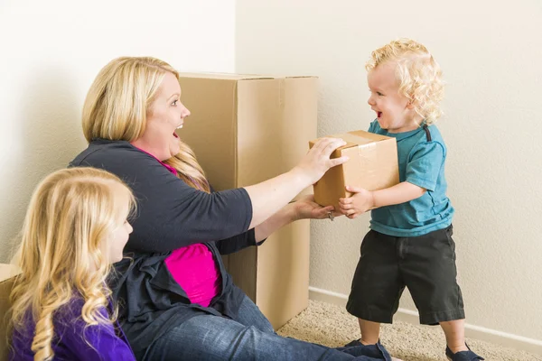 Familia joven en habitación vacía jugando con cajas móviles —  Fotos de Stock