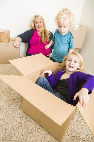 Familia joven en habitación vacía jugando con cajas móviles —  Fotos de Stock