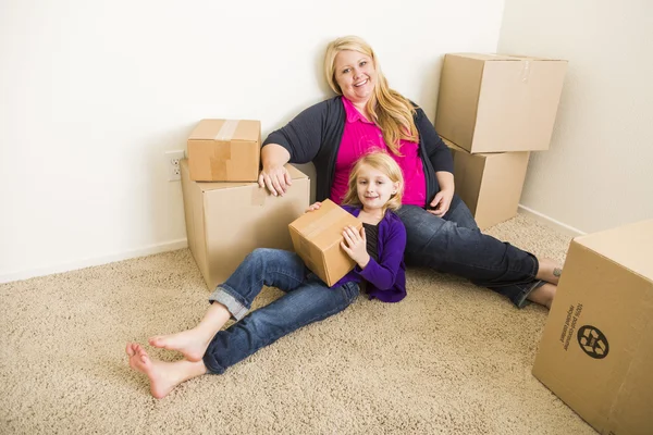 Joven madre e hija en habitación vacía con cajas móviles — Foto de Stock