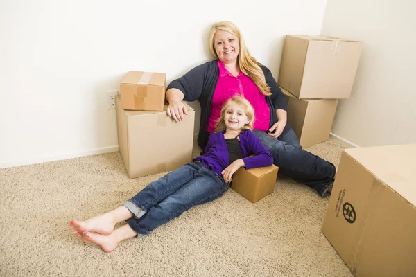 Joven madre e hija en habitación vacía con cajas móviles — Foto de Stock