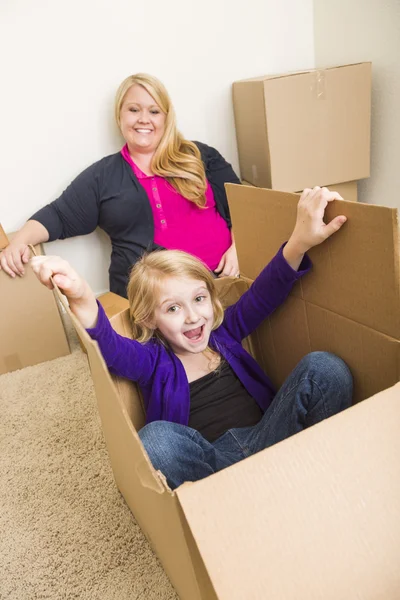 Familia joven en habitación vacía jugando con cajas móviles —  Fotos de Stock