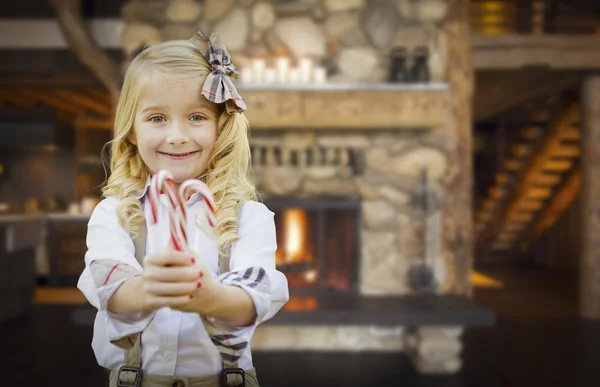 Cute Young Girl Holding Candy Canes in Rustic Cabin — Stock Photo, Image