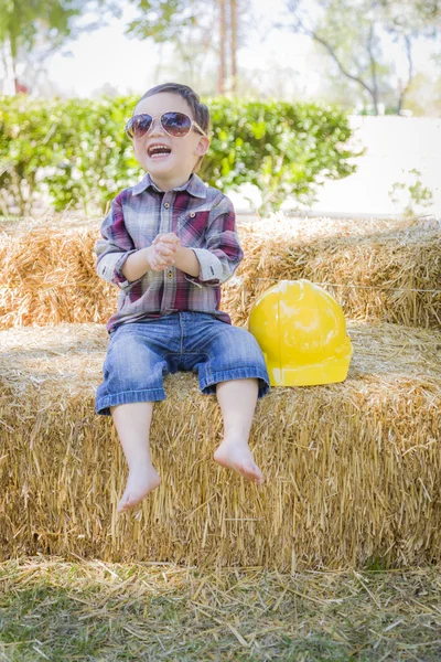 Joven mezclado raza chico riendo con gafas de sol y duro sombrero —  Fotos de Stock