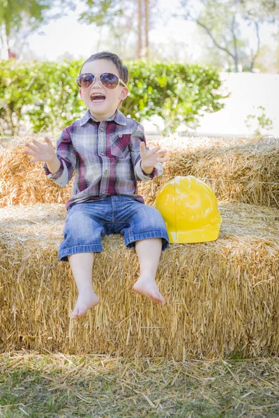 Joven mezclado raza chico riendo con gafas de sol y duro sombrero —  Fotos de Stock