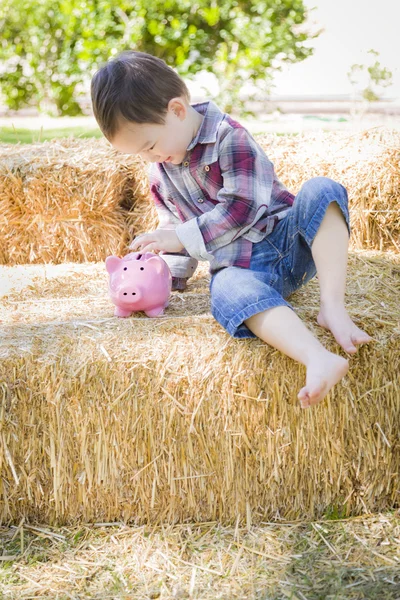 Cute młodych mieszane rasy chłopiec wprowadzenie monet do Piggy Bank — Zdjęcie stockowe