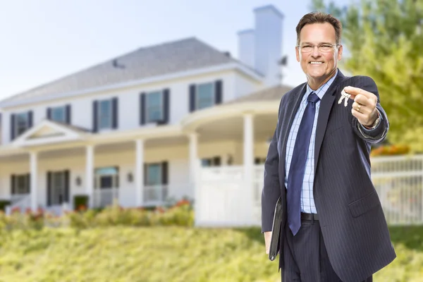 Fastighetsmäklare med huset nycklarna framför hemmet — Stockfoto