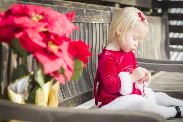 Чарівної маленької дівчинкою, сидячи на лавці з її цукерка — стокове фото