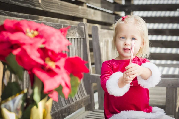 Rozkošná holčička sedí na lavičce s její Candy Cane — Stock fotografie