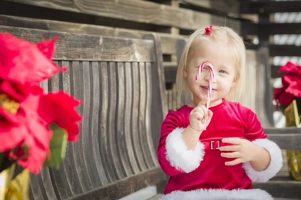 Onu şeker kamışı ile bankta oturan sevimli küçük kız — Stok fotoğraf