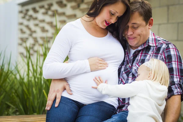 Entzückendes kleines Mädchen mit jungen schwangeren Eltern — Stockfoto