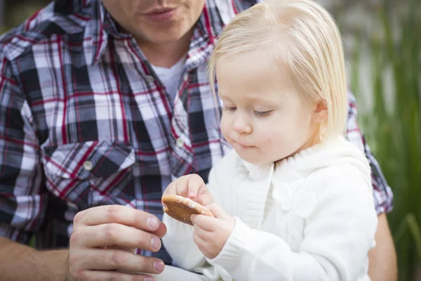 Adorable niña comiendo una galleta con papá —  Fotos de Stock