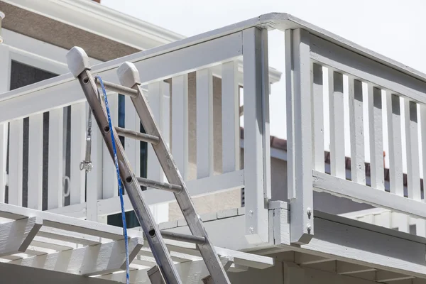 Escalera de construcción y manguera de pintura apoyada en la cubierta de la casa —  Fotos de Stock