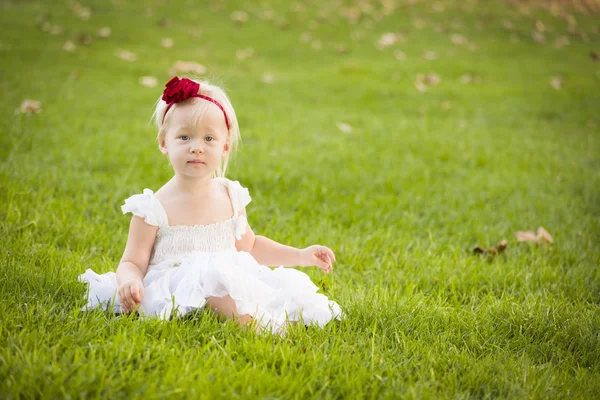 Adorável menina vestindo vestido branco em um campo de grama — Fotografia de Stock