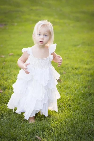 Adorável menina vestindo vestido branco em um campo de grama — Fotografia de Stock