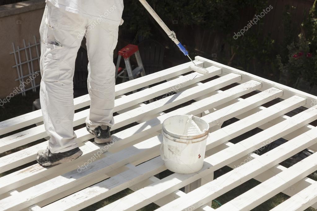 Painter Rolling White Paint Onto Top of Patio Cover