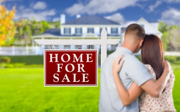 Prodej nemovitostí znamení, vojenské pár při pohledu na dům — Stock fotografie