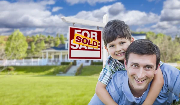 Gemengd ras vader, zoon piggyback, voorkant van huis, verkocht teken — Stockfoto