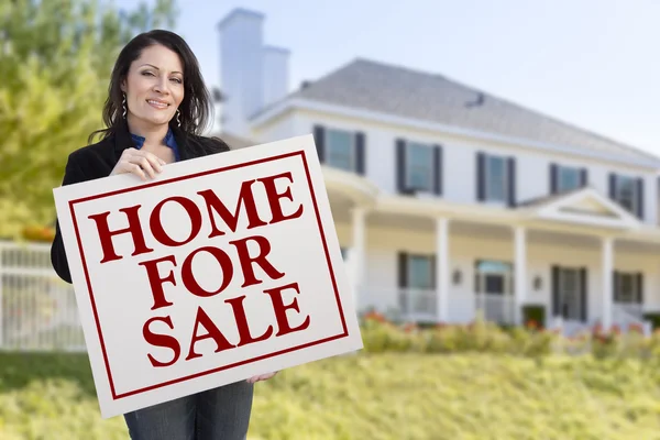 Mujer sosteniendo casa en venta Señal en frente de la casa — Foto de Stock