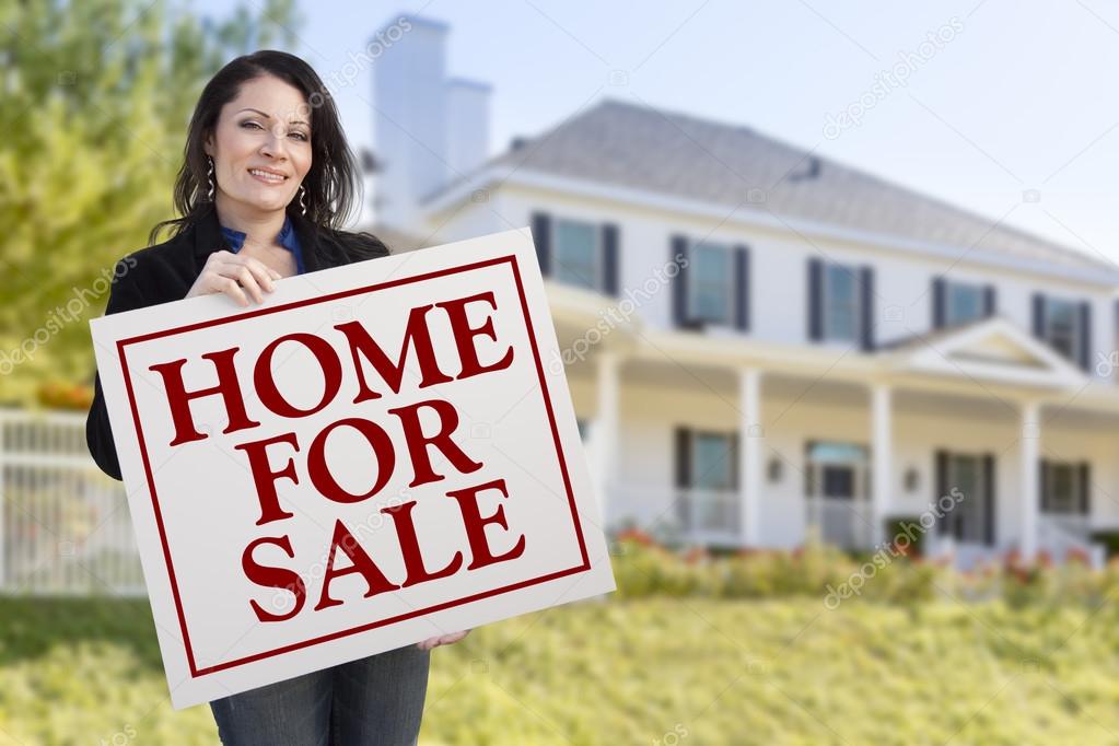 Woman Holding Home For Sale Sign in Front of House