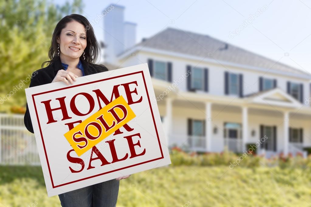 Woman Holding Sold Home Sale Sign in Front of House