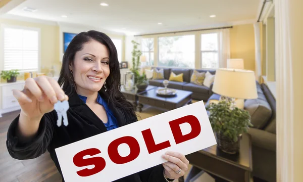 Hispanic Woman with Keys and Sold Sign in Living Room Royalty Free Stock Photos