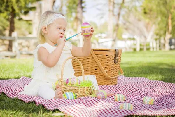 Linda niña para colorear huevos de Pascua en la manta de picnic —  Fotos de Stock