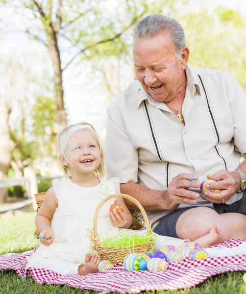 Grandfather and Granddaughter Coloring Easter Eggs on Blanket At Stock Picture