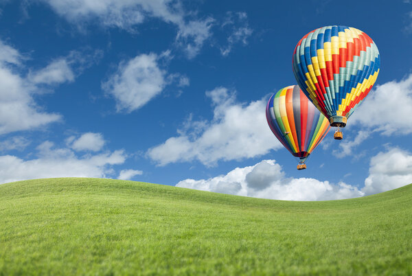 Hot Air Balloons In Beautiful Blue Sky Above Grass Field 