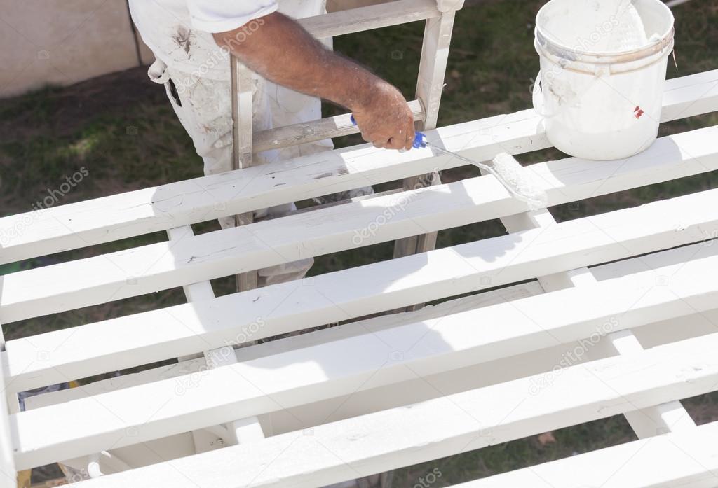 Painter Rolling White Paint Onto Top of Patio Cover