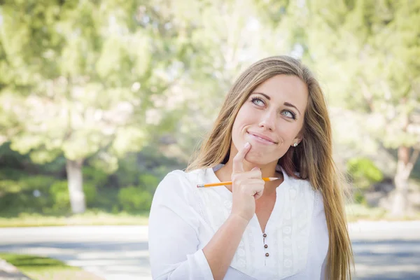 Besinnliche junge Frau mit Bleistift draußen — Stockfoto