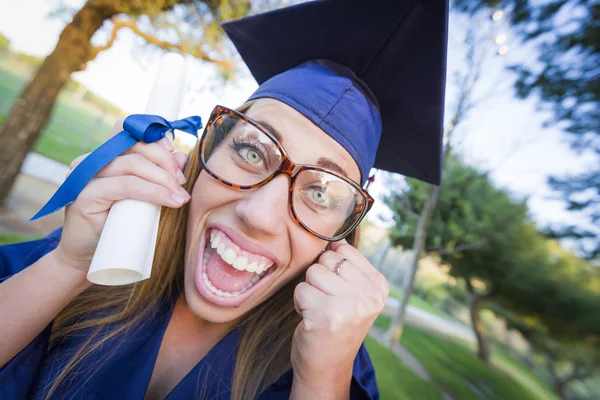 Експресивна молода жінка тримає диплом в шапці і сукні — стокове фото