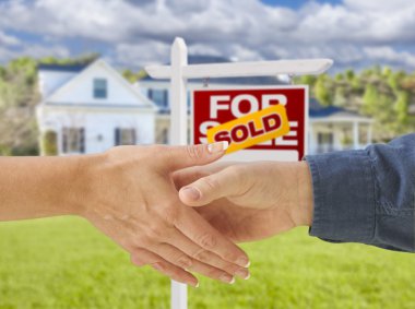 Yeni ev ve satılan işareti önünde el sıkışan