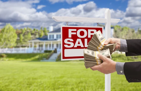 Mężczyzna przekazania pieniędzy przed Dom na sprzedaż, znak — Zdjęcie stockowe
