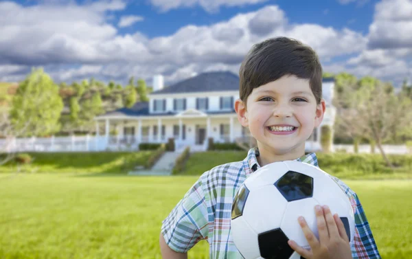 Усміхнений молодий хлопчик тримає футбольний м'яч перед будинком — стокове фото