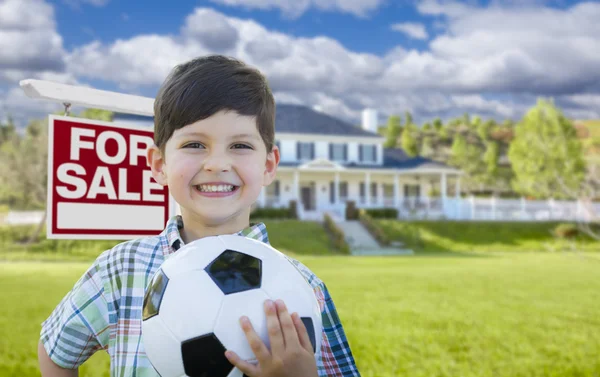 Jongen houden bal voor huis en verkoop teken — Stockfoto