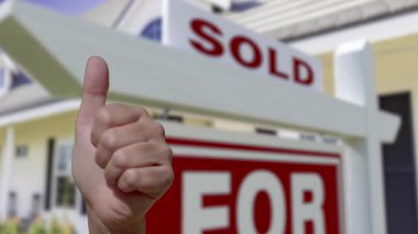 Satılık Gayrimenkul Tabelası ve Güzel Yeni Ev İşareti Önünde Başparmağıyla Bir Kadın Eli.