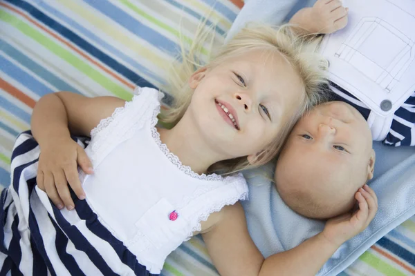 Kleine Schwester liegt neben ihrem kleinen Bruder auf Decke — Stockfoto