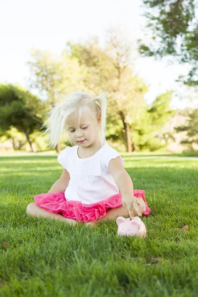 Malá holčička se baví s její prasátko mimo — Stock fotografie