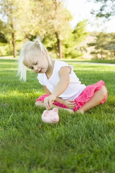 Kleines Mädchen hat Spaß mit ihrem Sparschwein draußen — Stockfoto