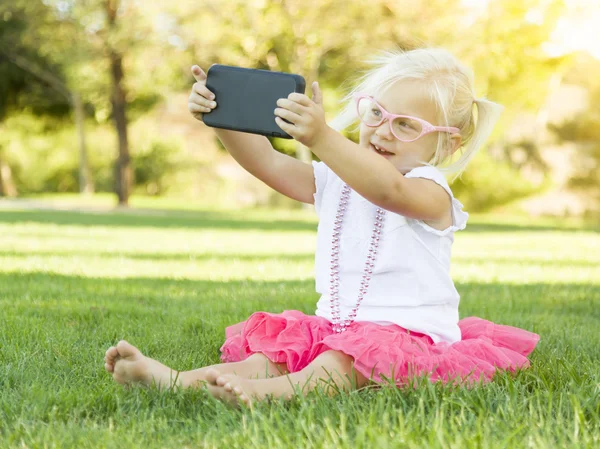 Девочка в траве делает селфи с сотовым телефоном — стоковое фото