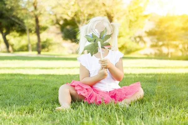 Petite fille dans l'herbe soufflant sur Pinwheel — Photo
