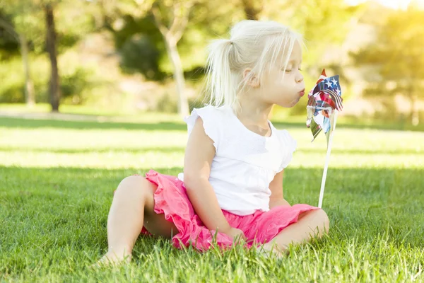Petite fille dans l'herbe soufflant sur Pinwheel — Photo