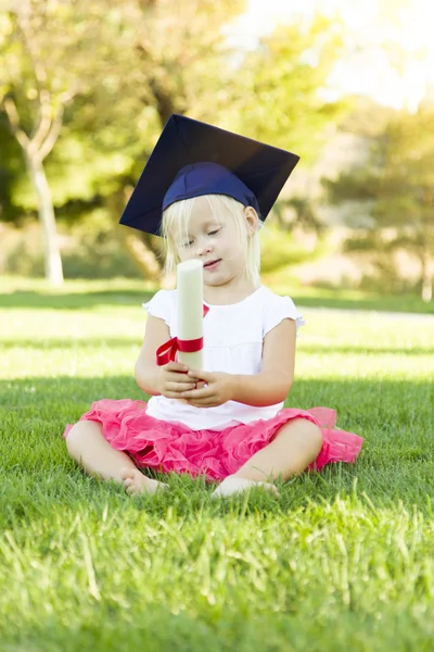 Little Girl In Grass Wearing Graduation Cap Holding Diploma With — Stock Photo, Image